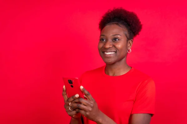 Młoda Afroamerykanka Odizolowana Czerwonym Tle Uśmiechnięta Telefonem Komórkowym Sesja Naukowa — Zdjęcie stockowe