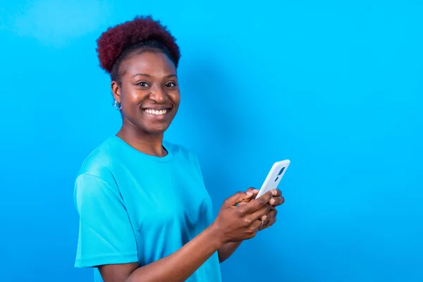 Νεαρή Αφροαμερικανή Γυναίκα Απομονωμένη Μπλε Φόντο Χαμογελώντας Κινητό Τηλέφωνο Συνεδρία — Φωτογραφία Αρχείου