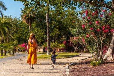 Oğluyla birlikte Kanarya Adaları 'ndaki Tenerife adasında palmiye ağaçları olan bir parkta tatil yapan bir anne.