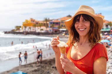 Yazın plajda dondurma yiyen şapkalı turist kadın La Gomera, Kanarya Adaları 'ndaki Valle Gran Rey plajında