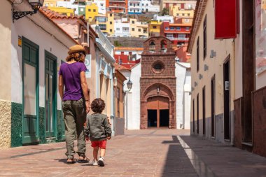 Tatil konsepti, annesi ve oğlu San Sebastian de la Gomera 'da yürüyorlar Iglesia De La Asuncion, Kanarya Adaları' nın yanında.