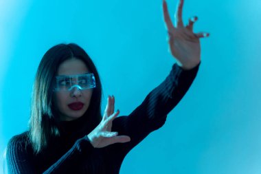 Metaverse teknoloji konsepti. Mavi arka planda fütürist gözlüklü bir kadın. Geleceğe yönelik