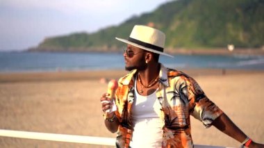 Zenci etnik adam yaz tatilinde sahilde dondurma yiyip eğleniyor.