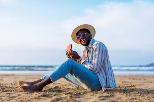 미소를 수박을 먹으며 해변에서 휴가를 즐기는 흑인의 — 스톡 사진