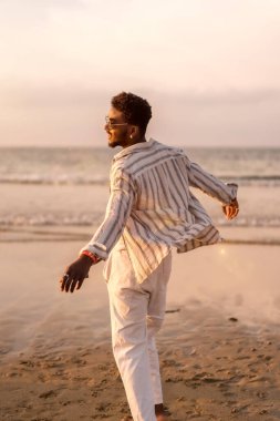 Çekici zenci adamın portresi deniz kenarında yaz tatilinin tadını çıkarıyor özgür hissediyor ve dans ediyor.