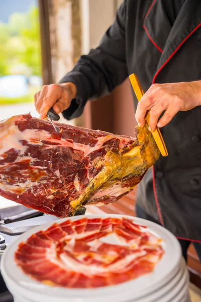 Stock image Detail of a man cutting Iberian ham at a wedding. Service of a person cutting a piece of ham. Chef or cutter with a knife cutting slices. traditional food of spain