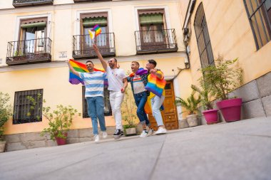 Homoseksüel erkek arkadaşlar sevinçten gay onur partisine atlıyorlar, şehirdeki gençlerin çeşitliliği, gökkuşağı bayraklarıyla gösteriye giden yol, lgbt konsepti