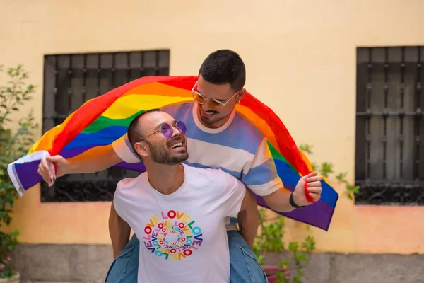 同性男伴背靠背骑着彩虹彩旗的骄傲派对 Lgbt概念 — 图库照片