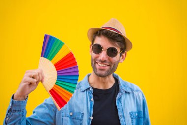 Sarı arka planda gökkuşağı lgbt fanı olan beyaz bir adam.