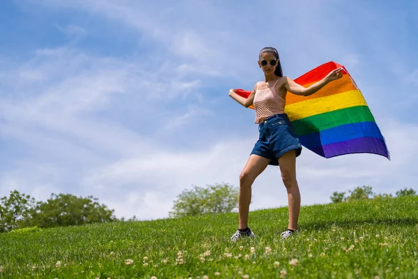 白种人的黑发女人 带着彩虹Lgbt旗在草地上微笑 — 图库照片