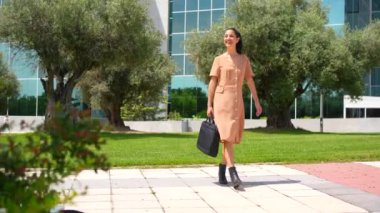 Bilgisayarlı evrak çantasıyla yürüyen Latin kadın yönetici ya da iş kadını