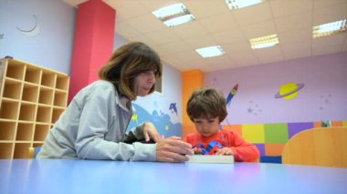 Anaokulunun içinde oturmuş masal kitabı okuyan bir kadın öğretmenin portresi.