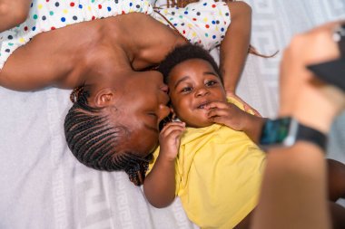 Afrikalı siyahi anne ve küçük oğlu yataktaki odada, yukarıdan çekilmiş.