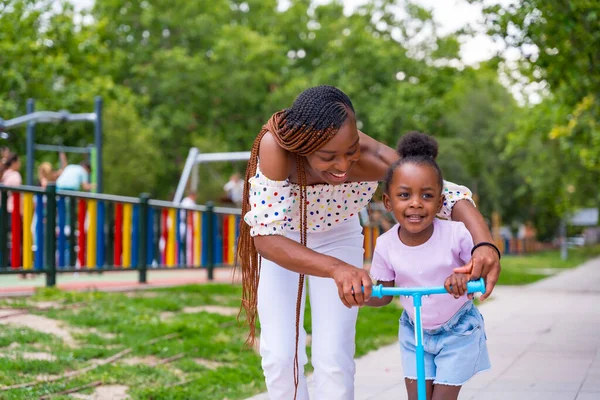 Musta Afrikkalainen Etnisyys Äiti Hauskaa Tyttärensä Kanssa Leikkikentällä Oppiminen Ratsastaa — kuvapankkivalokuva