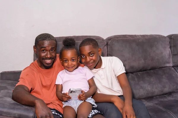 아프리카 아버지 소파에 자녀가 집에서 전화기를 — 스톡 사진