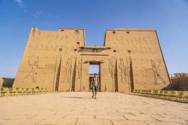 Genç bir turist Edfu, Mısır 'daki Edfu Tapınağı' na giriyor. Nil nehrinin kıyısında, kertenkele-Roma inşaatı, Huros 'a adanmış tapınak.