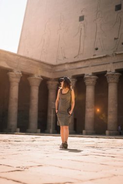 Aswan 'da güneş doğarken Edfu Tapınağı' nı ziyaret eden şapkalı genç bir turist. Mısır, sabahleyin boş tapınakla.