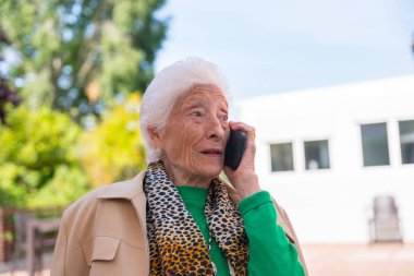 Huzurevinin bahçesinde yaşlı bir adam ya da güneşli bir yaz gününde huzurevinde telefonla konuşan, yaşlılar için teknolojileri olan bir adam.