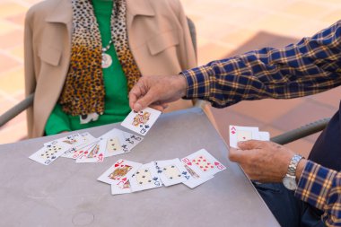 Huzurevinin bahçesinde iki yaşlı insanın elleri ya da bir yaz sabahı kart oynayan huzurevi.