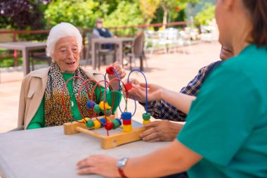 Huzurevinin bahçesinde ya da huzurevinde hareketliliği artırmak için oyunlarla oynayan iki yaşlı insan.