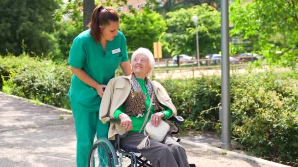 自然と隣接する車椅子の老人ホームの庭を歩く看護師の高齢女性 — ストック動画