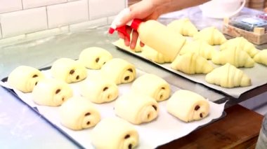 Esnaf fırınının atölyesinde fırın fırıncısı kruvasan yerleştiriyor.