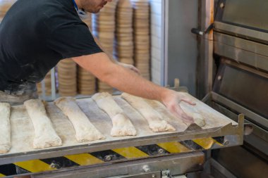 Erkek fırıncı, atölye atölyesinde fırında fırın somunları yapıyor.