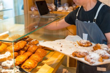 Esnaf fırınının atölyesinde tanınmayan fırıncı kruvasan ve Napoli kruvasanı yerleştiriyor.