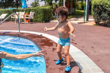 Anne ve oğul yaz tatilinde havuza atlıyorlar.