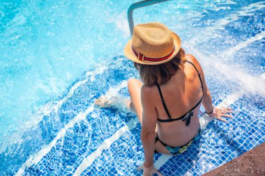 Havuzdaki şapkalı kadın tatil için kaplıcaya gitti. Yaz rahatlatıcı kavram