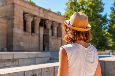 Mısır 'ın Madrid şehrindeki Debod Tapınağı' nda gün batımında eski Mısır tapınağında şapkalı genç bir turist kadın.