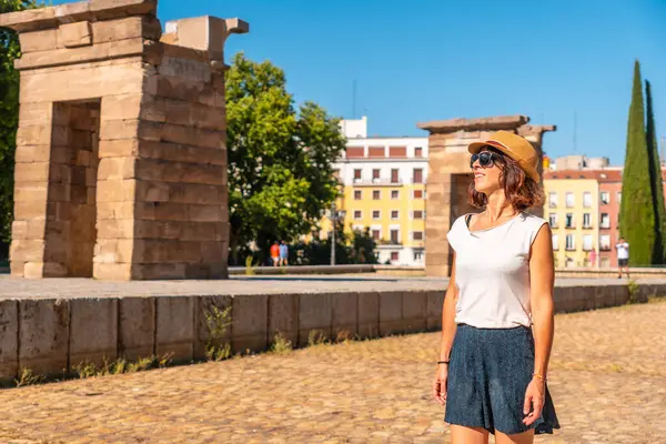 Madrid, Mısır 'daki Debod Tapınağı. Eski Mısır tapınağında yaz tatilinde şapkalı turist kadın.