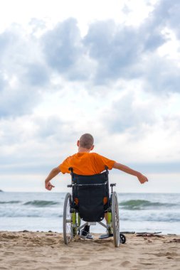 Yazın sahilde tekerlekli sandalyede sırtüstü yatan engelli biri.