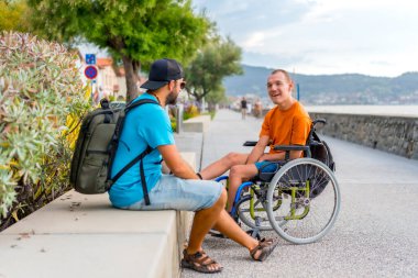 Yaz tatilinde arkadaşlarıyla tekerlekli sandalyede olan engelli biri.
