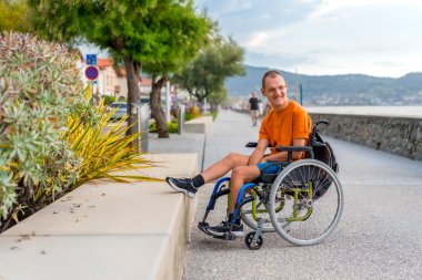Yaz tatilinde sahilde tekerlekli sandalyede oturan engelli biri.