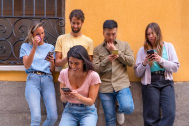 Şehirdeki telefona gülümseyen bir grup çok ırklı arkadaş.
