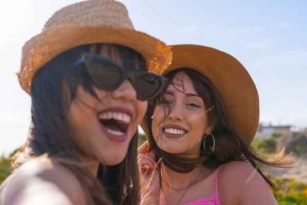 バケーションで帽子をかぶった女性の友達のクローズアップ ビーチでセルフィーを取る 電話で笑顔 — ストック写真