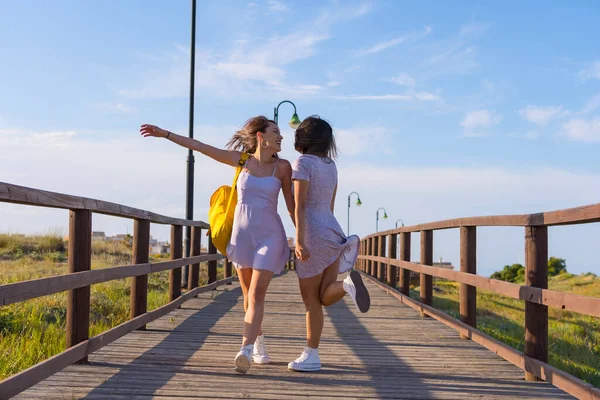 在海滨的暑假里 女性朋友们走在一条木制的小径上 兴奋地跳着 — 图库照片