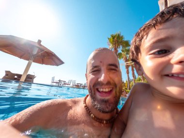 Baba ve oğulun yazın havuzda çekilmiş selfie 'si tatilin tadını çıkarıyor.
