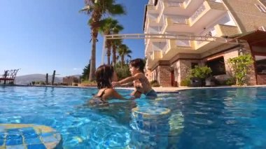 Anne ve oğlu yazın havuzda tatilin tadını çıkarıyorlar.