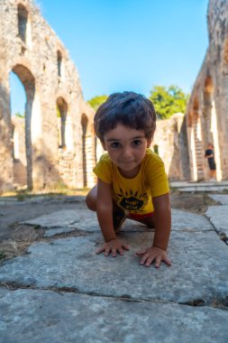 Arnavutluk 'taki Butrint veya Butrinto Ulusal Parkı arkeolojik kalıntılarında Büyük Bazilika' da oynayan bir çocuk