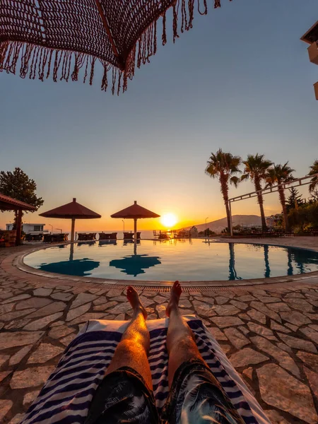 Feet of a man in a pool enjoying a sunset on summer vacation