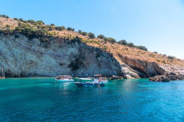  Sarande yakınlarındaki Arnavut Rivierası 'ndaki tekneden görülen Gremina sahilindeki turistik tekneler, turkuaz deniz suyu