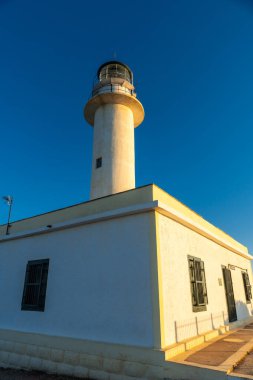 Lefkada adasının güney bölgesinde gün batımında beyaz deniz feneri veya Ducato Lefkas Burnu. Yunanistan.