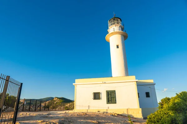 Lefkada adasının güney bölgesinde gün batımında beyaz deniz feneri veya Ducato Lefkas Burnu. Yunanistan.
