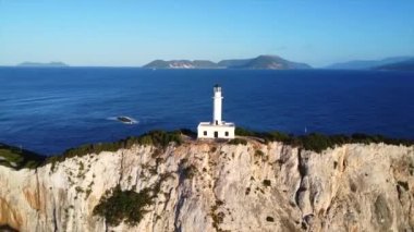 Lefkada adasının güney bölgesinde gün batımında beyaz deniz feneri veya Cape Ducato Lefkas 'ın insansız hava aracı görüntüsü. Yunanistan. Dönen pan düzlemi