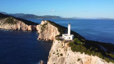 Uçurumların ve beyaz deniz fenerinin hava aracı görüntüsü ya da Lefkada adasının güney bölgesinde gün batımında Ducato Lefkas Burnu. Yunanistan. Dönen pan düzlemi