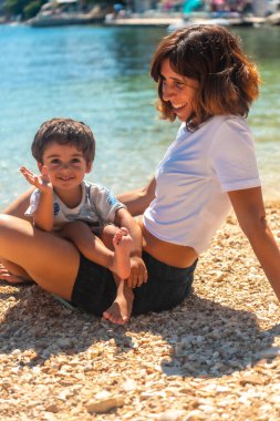 Yunanistan 'ın Kefalonia adasındaki Fiskardo plajında gülümseyen bir anne ve oğulun portresi