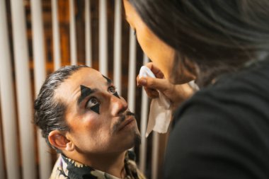 Cadılar Bayramı partisi hazırlıkları, makyözün müşteriye yüz boyamasını bitirmesi ve son dokunuşları kontrol etmesi.