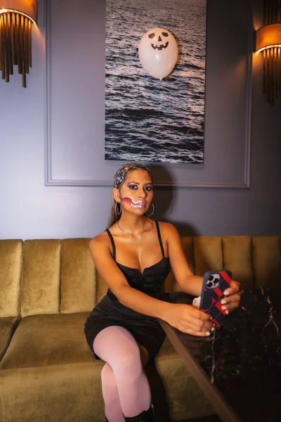 Halloween party with friends in a disco nightclub, portrait of a woman with makeup on a sofa